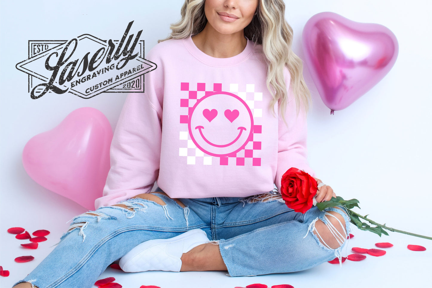 Model wearing a pink sweatshirt with a smiley face and checkers